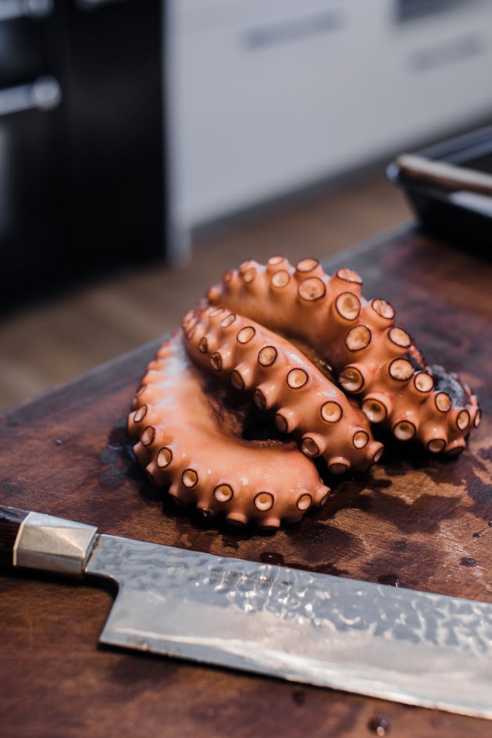 Cut raw octopus tentacles placed on table near sharp knife prepared for cooking