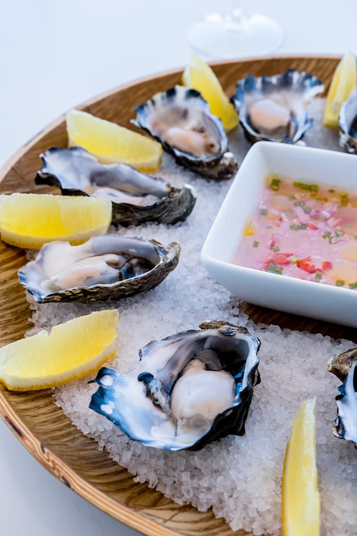 Opened Raw Oysters and Sliced Lemon on a Wooden Plate